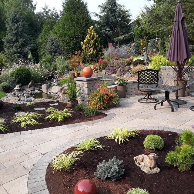 A garden with a table and chairs and a purple umbrella