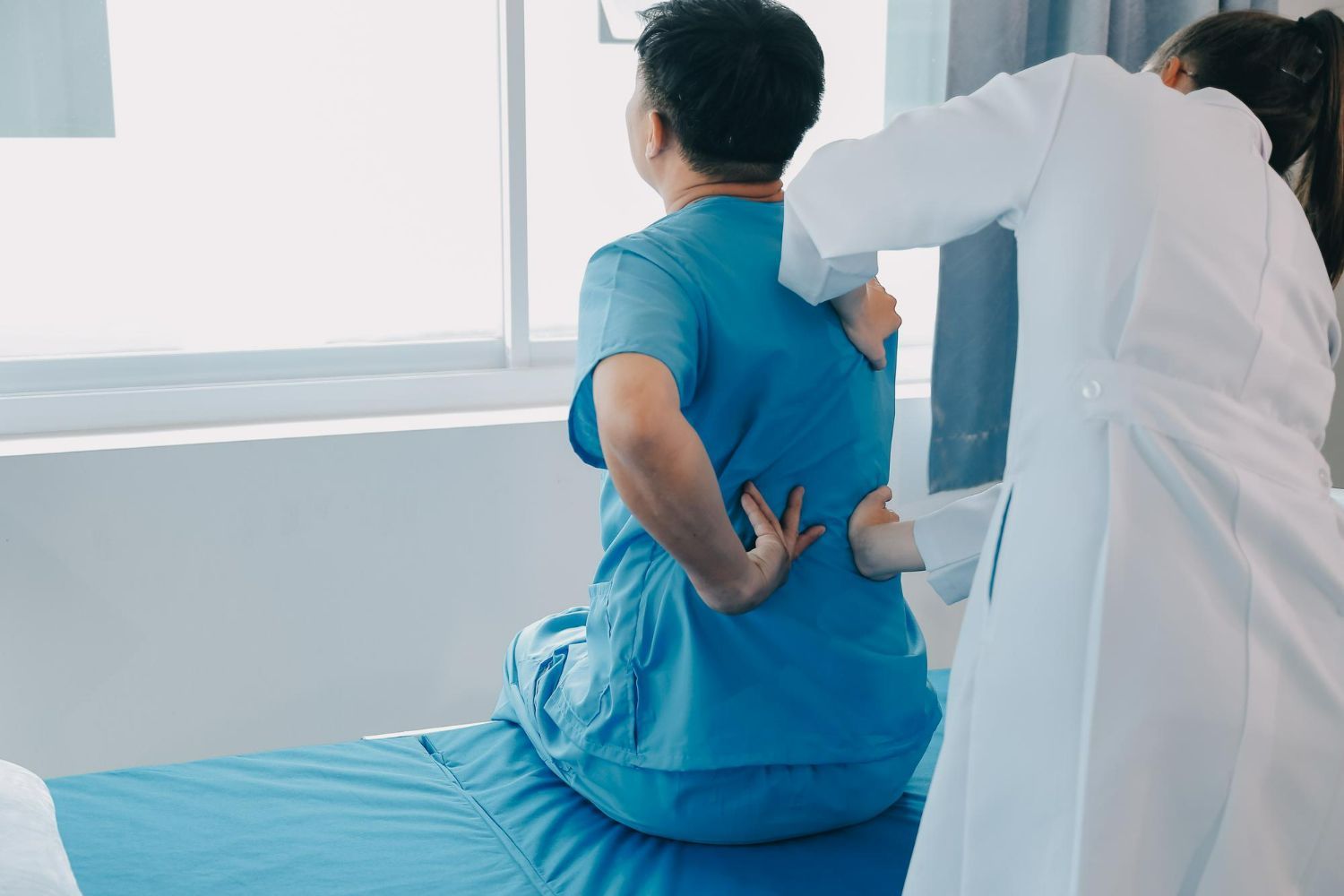 A doctor is helping a patient with his back pain.
