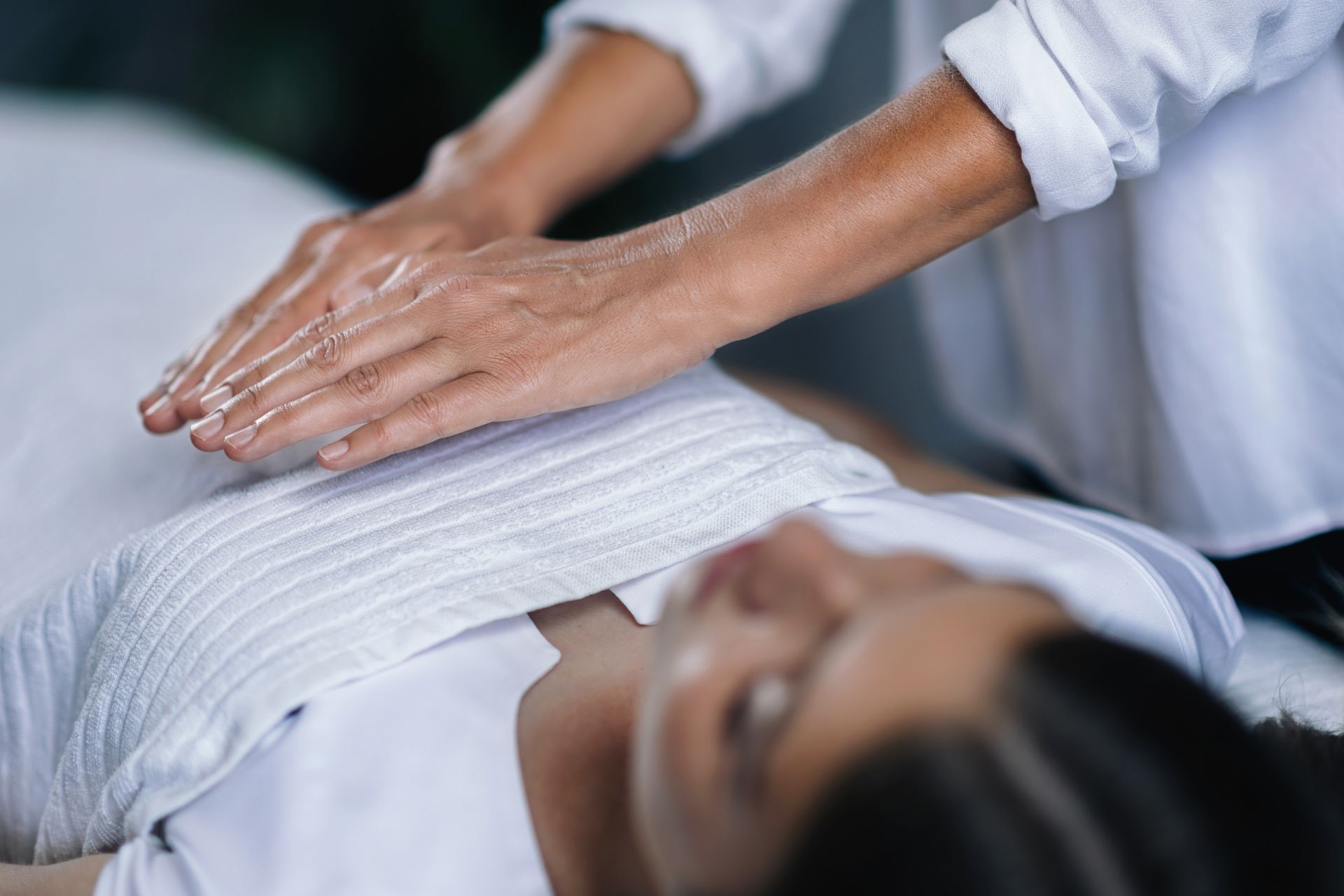 a woman is laying on a bed getting a reiki treatment .