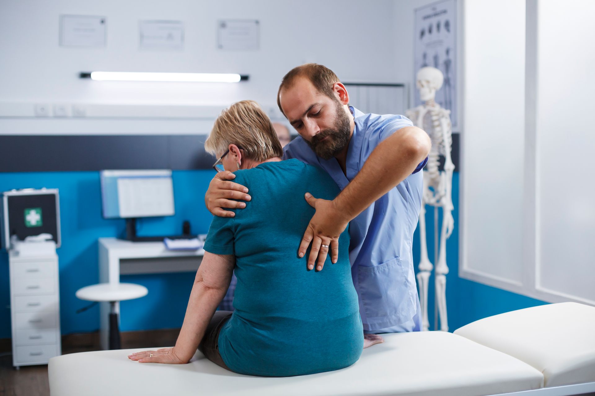 A doctor is examining a patient 's back in a hospital room.