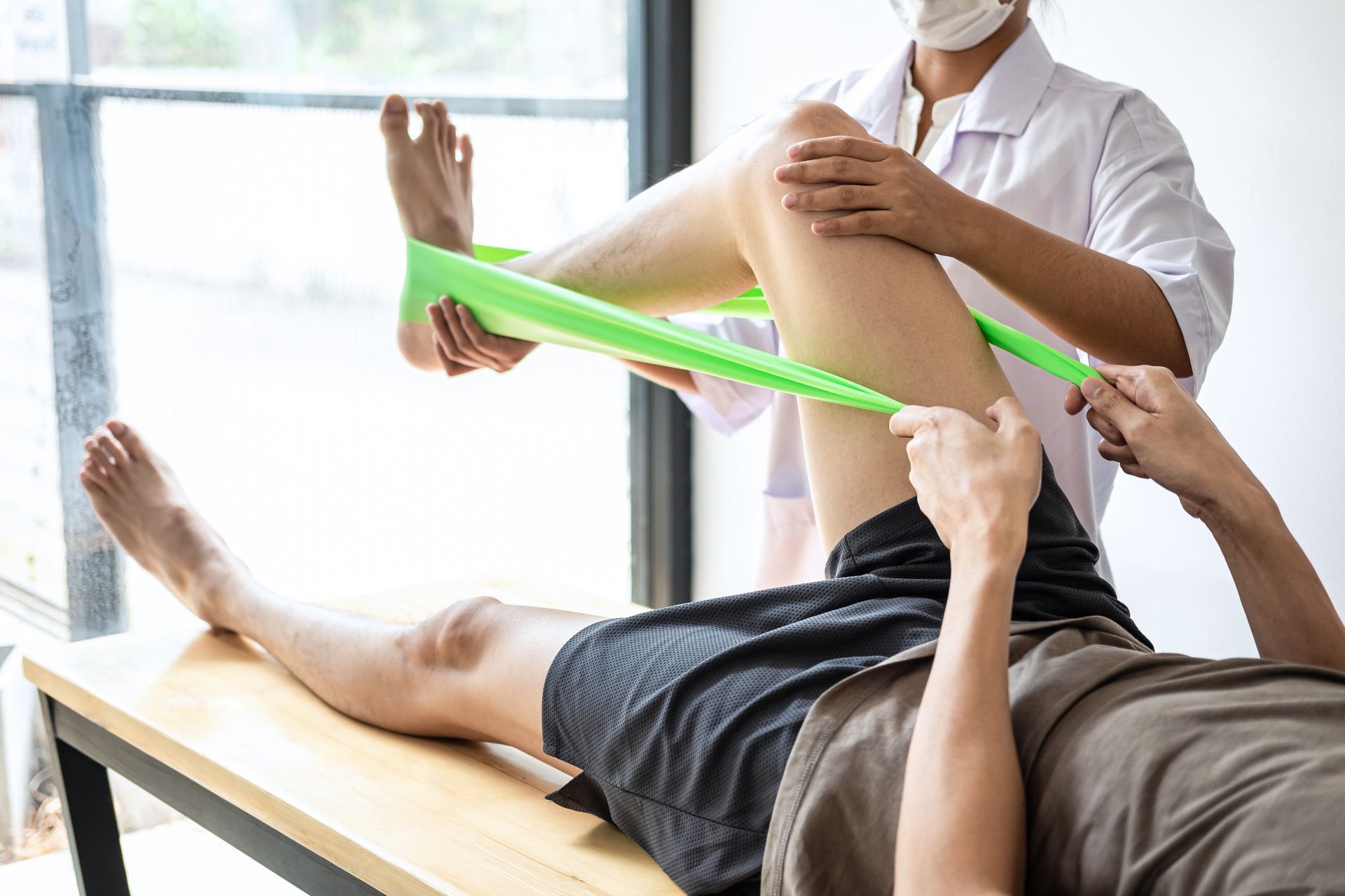 a doctor is stretching a patient 's leg with a green resistance band .