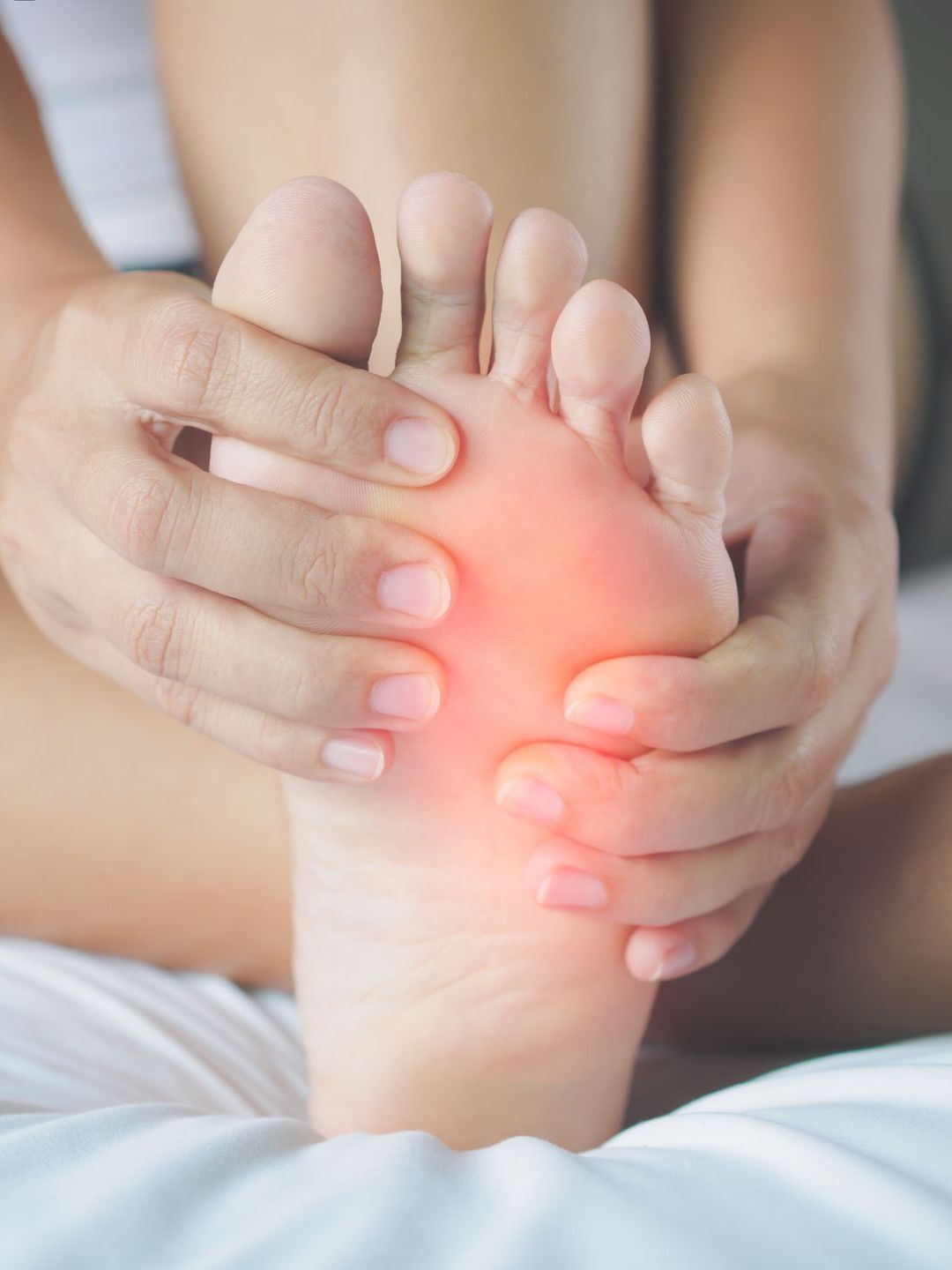 a woman is sitting on a bed holding her foot in pain .