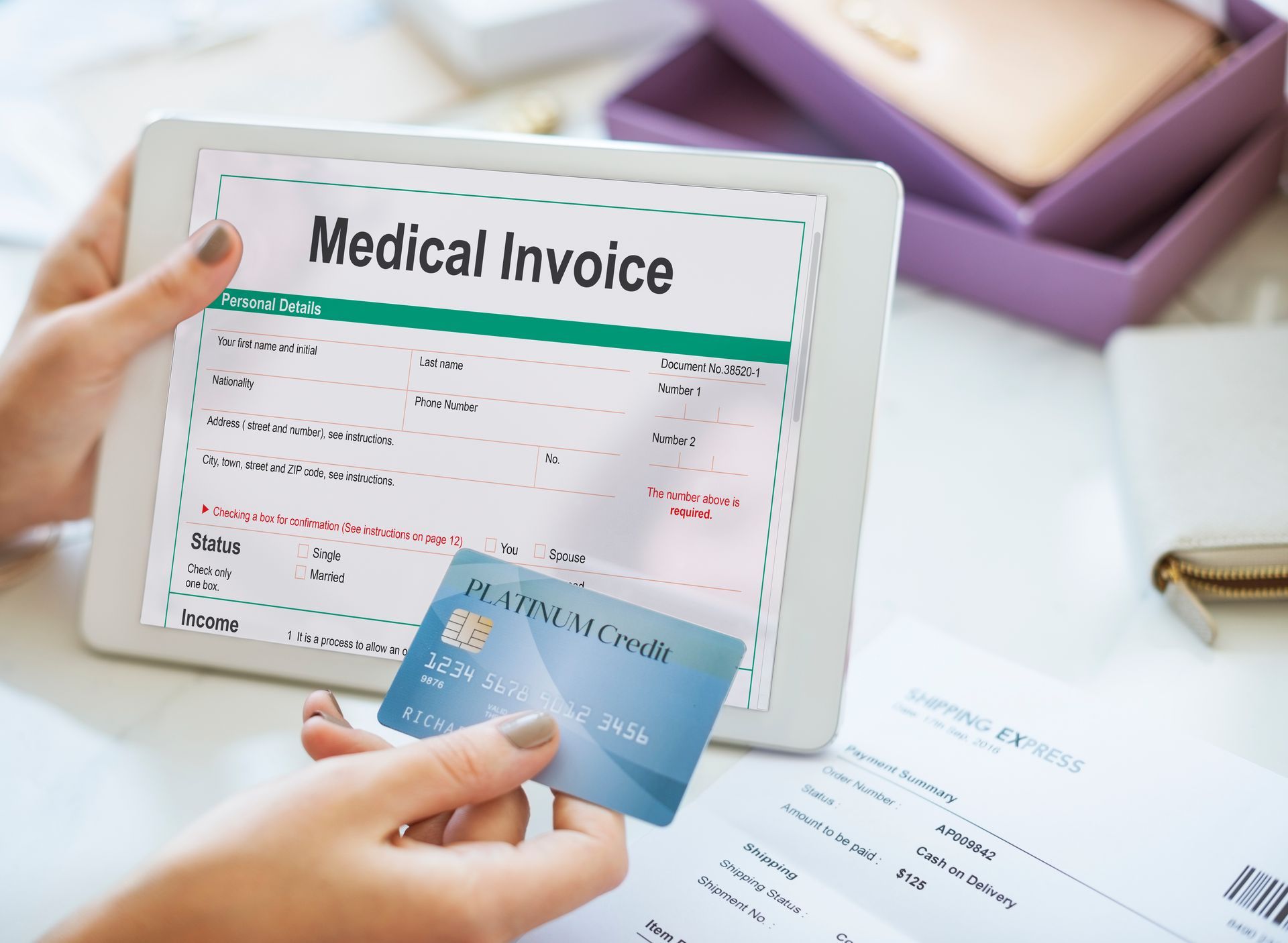 a person is holding a credit card in front of a tablet with a medical invoice on it .