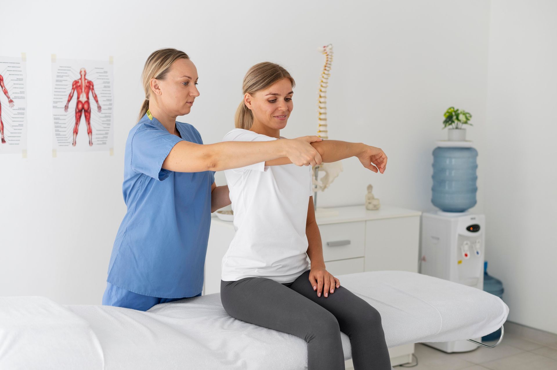 a woman is sitting on a bed while a nurse examines her arm .