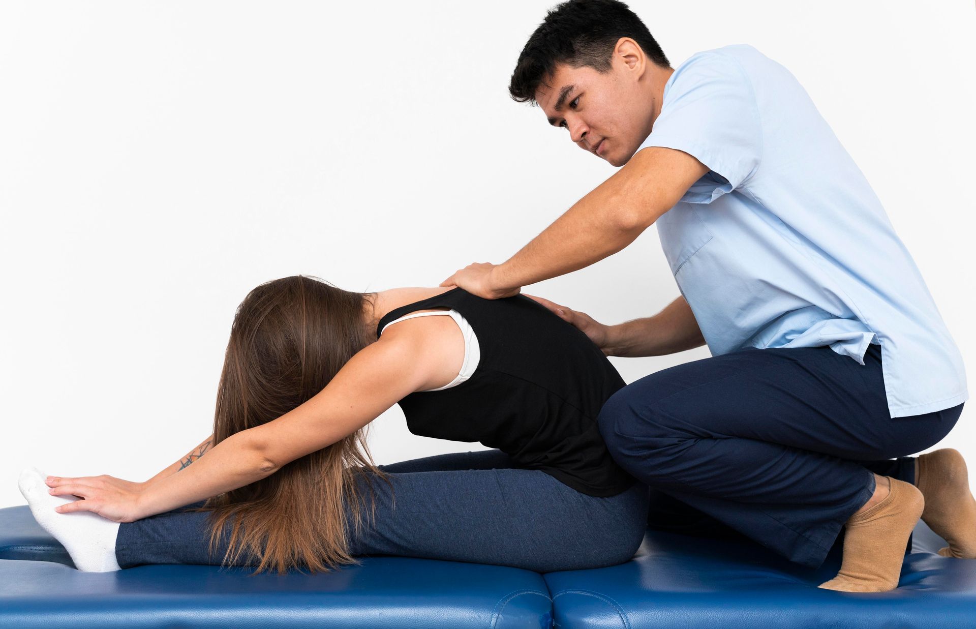 A man is stretching a woman 's back on a table.