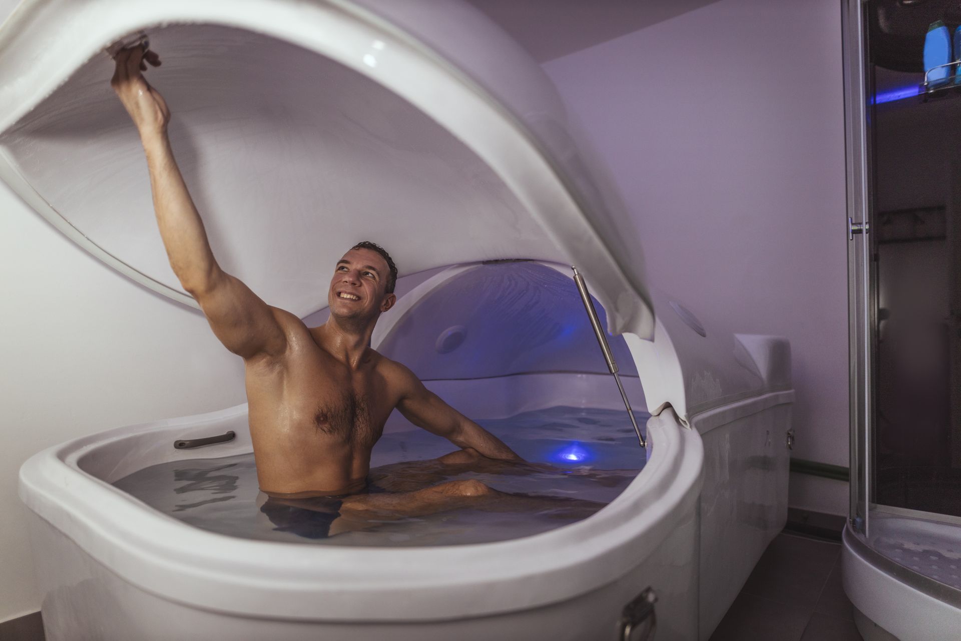 a shirtless man is floating in a bathtub with the lid open .