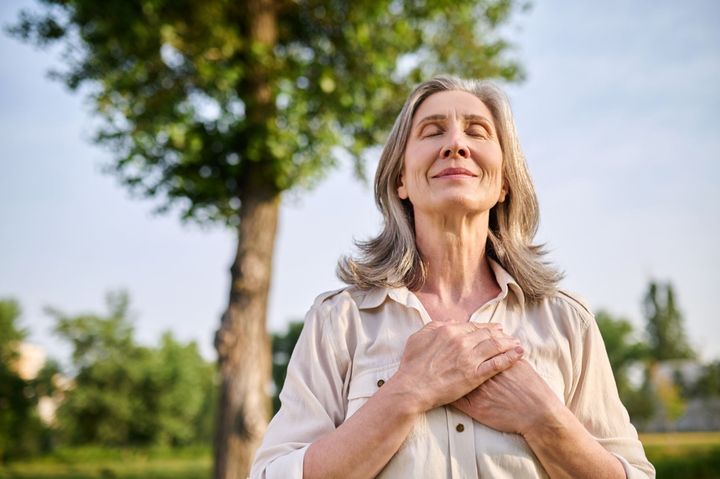 a woman is standing in a park with her arms outstretched .