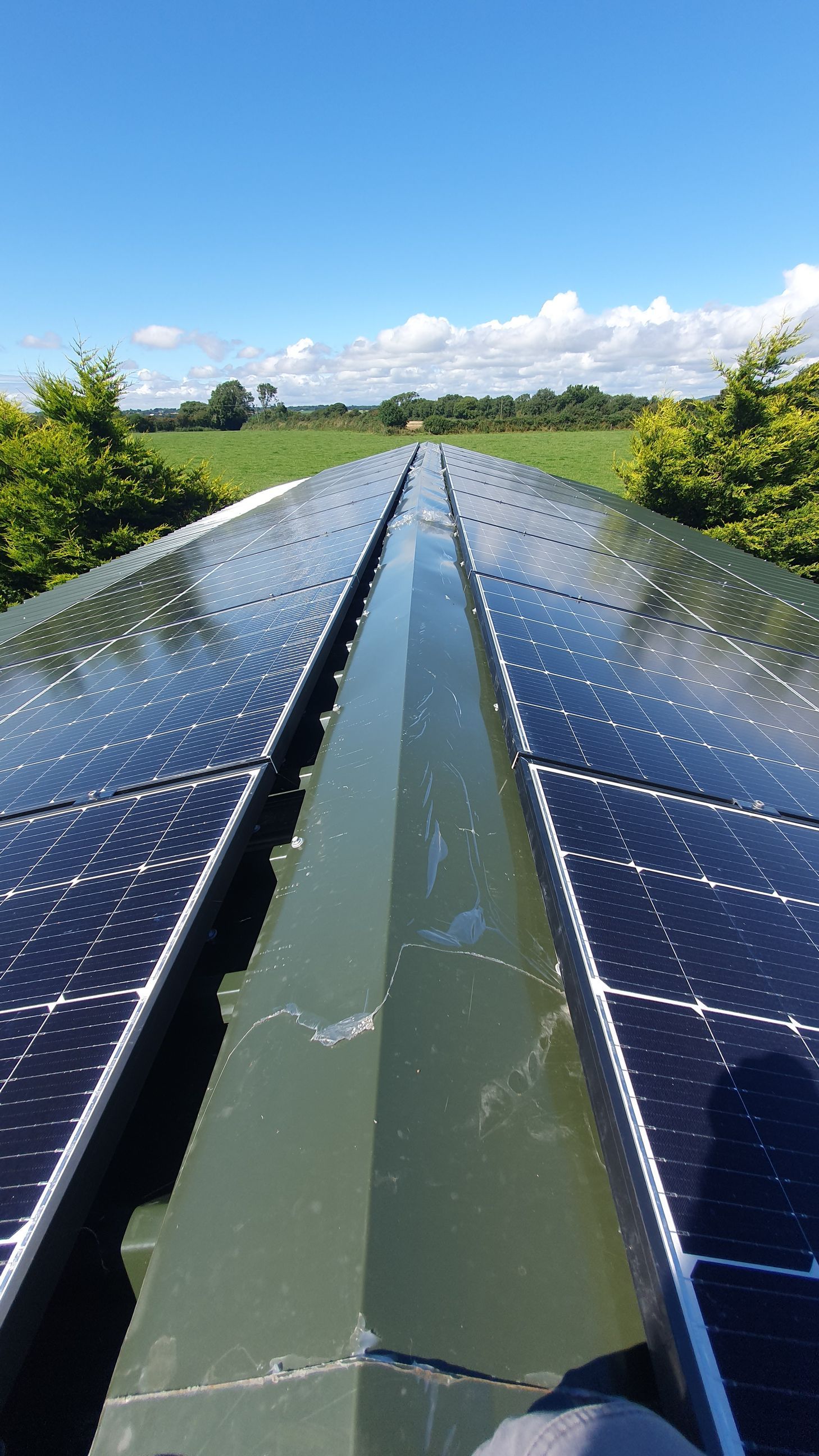 A row of solar panels on a roof with a blue sky in the background.