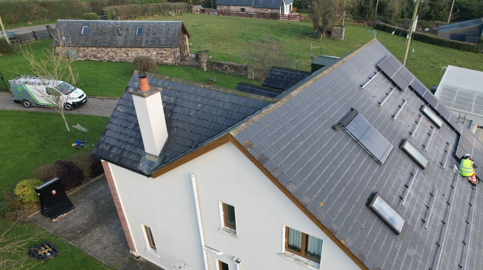 An aerial view of a house with a solar panel on the roof.