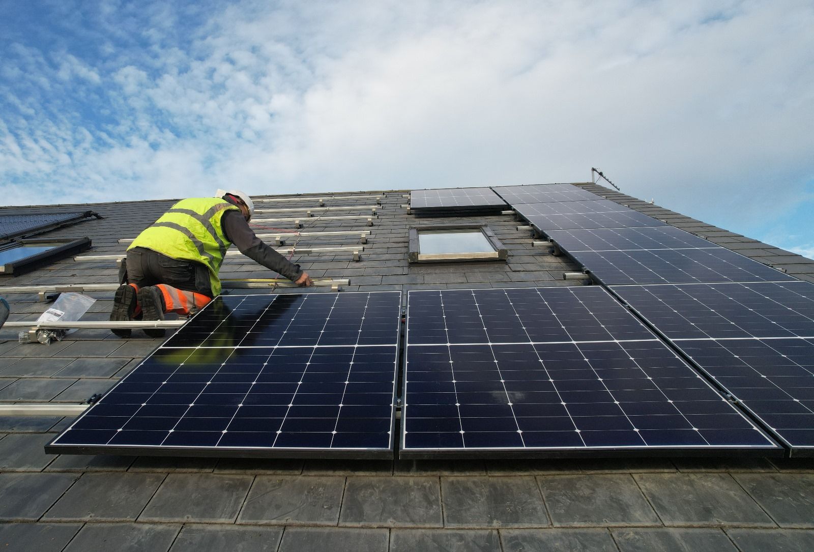 A man is installing solar panels on a roof.