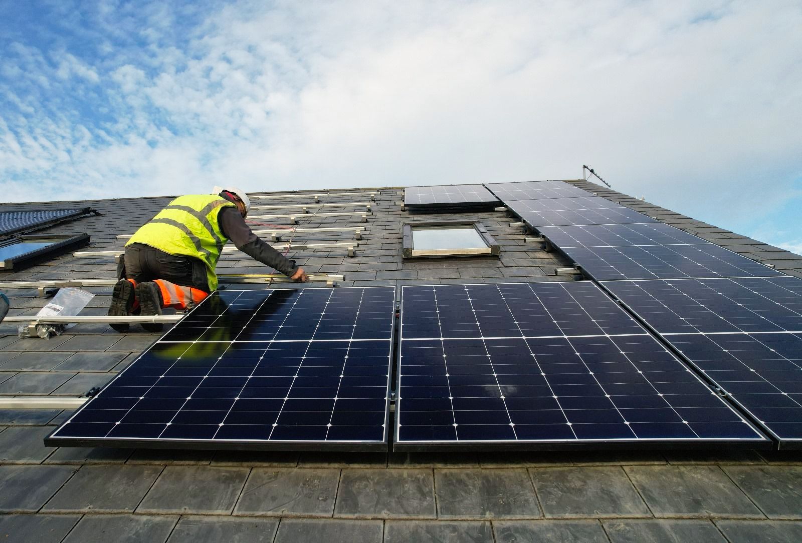 A man is installing solar panels on a roof.