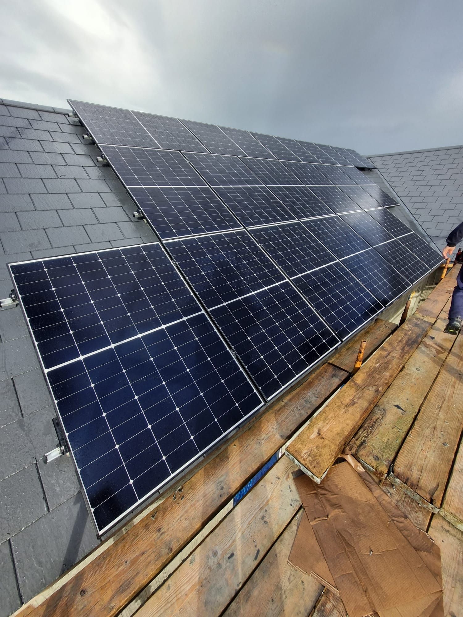 A man is working on a roof with solar panels.