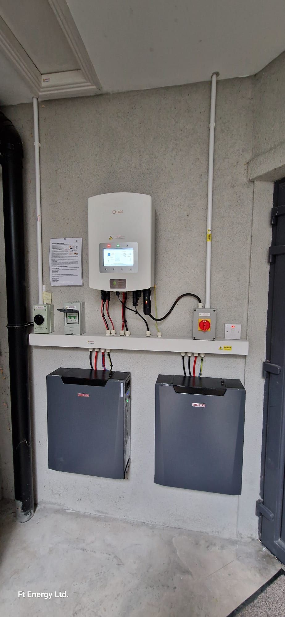 A solar panel is sitting on top of a wall next to two batteries.