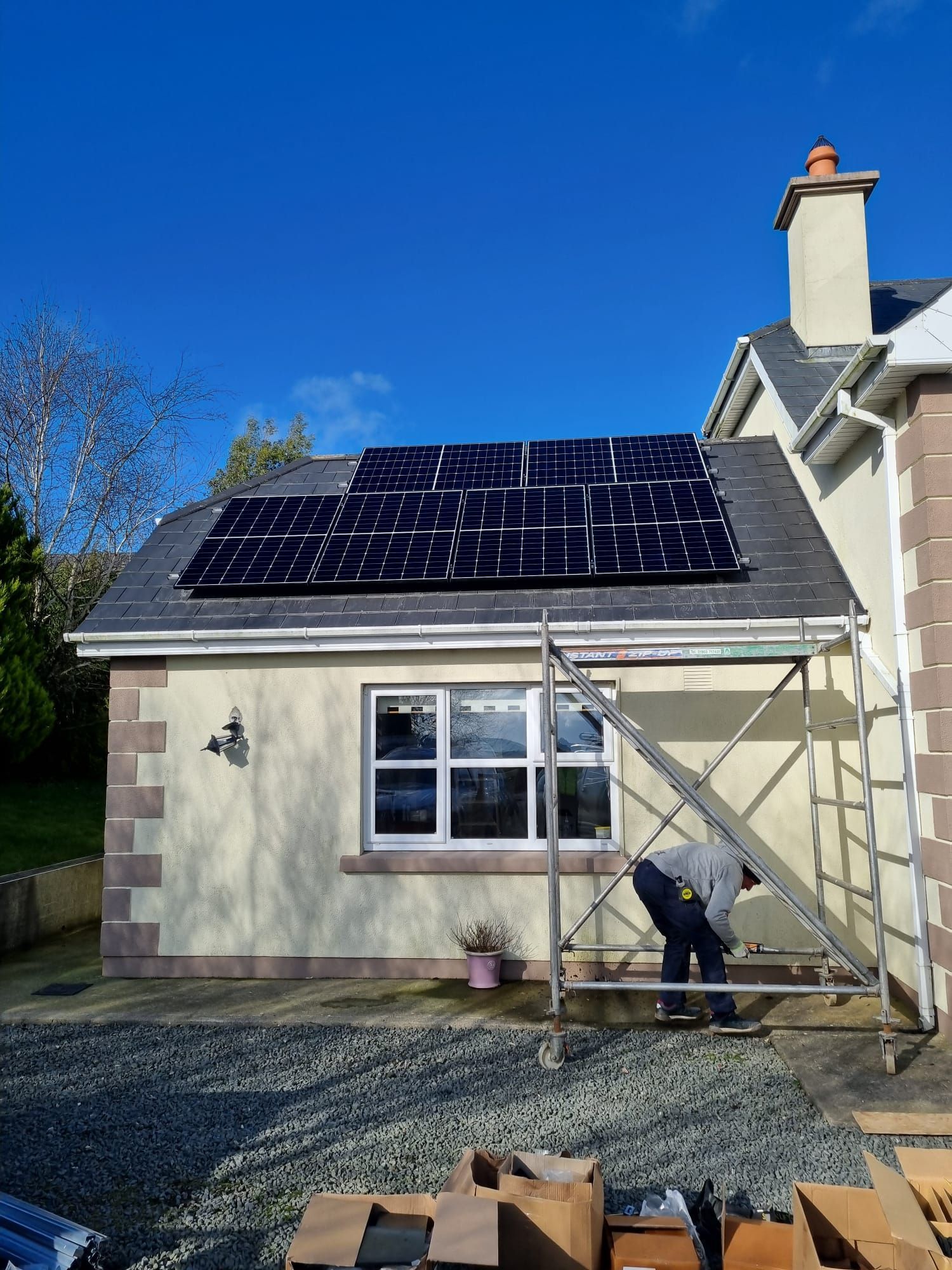 A man is installing solar panels on the roof of a house.