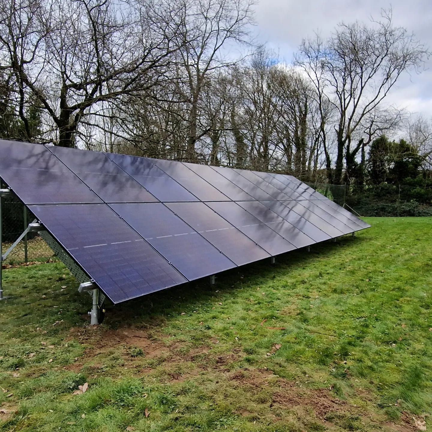 A large solar panel is sitting in the middle of a grassy field.