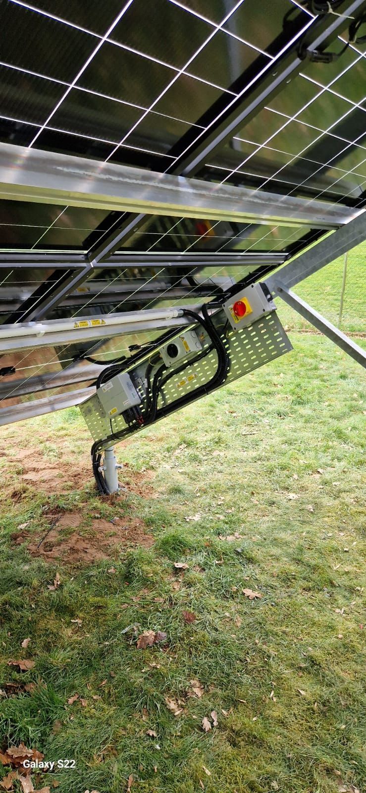 A solar panel is sitting on top of a lush green field.