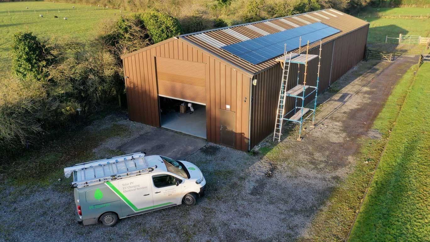 An aerial view of a building with solar panels on the roof and a van parked in front of it.