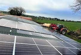 A tractor is driving down a hill next to a field of solar panels.