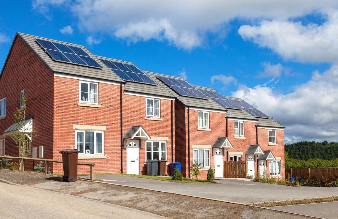 A row of brick houses with solar panels on the roofs.