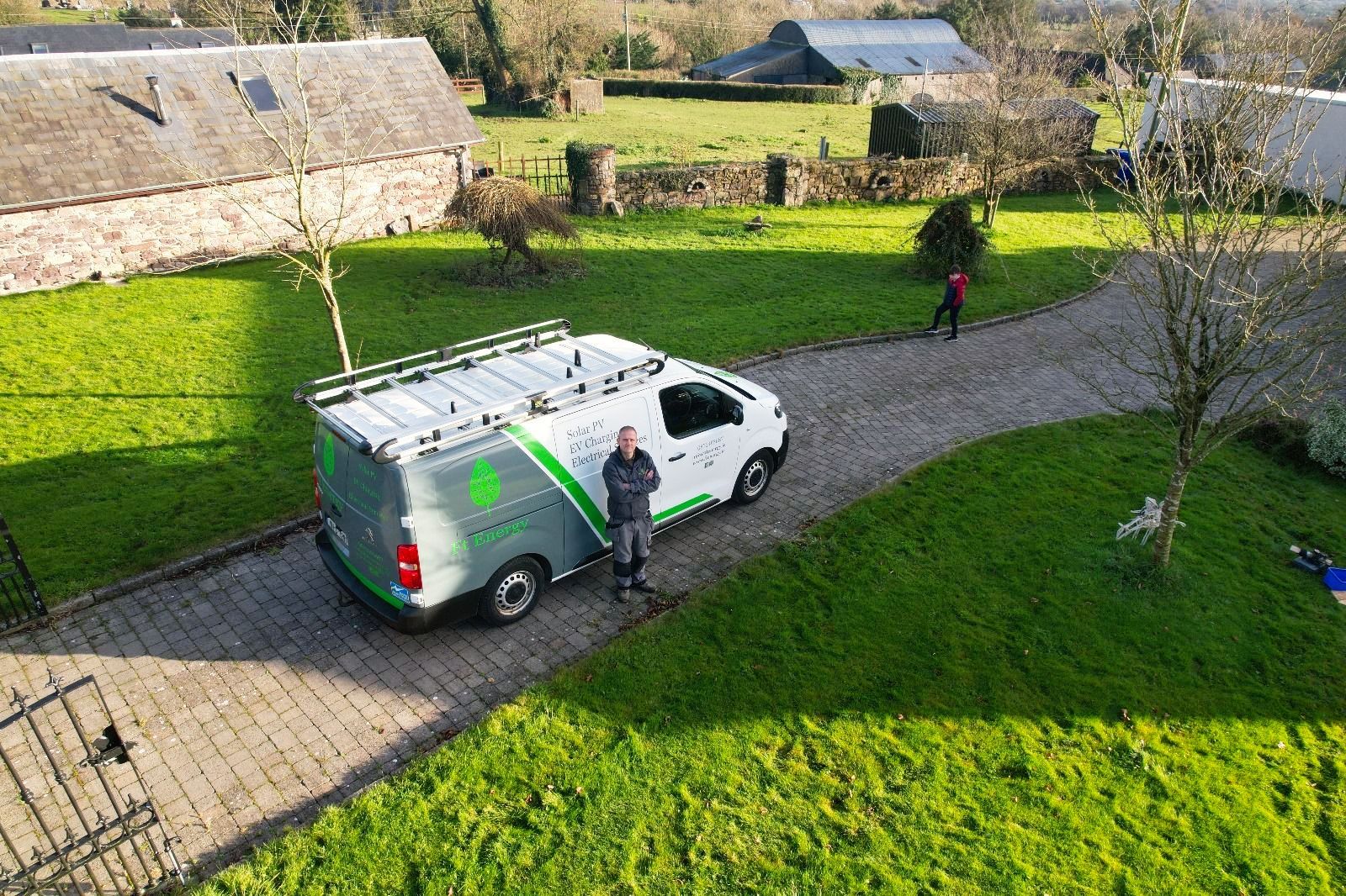 An aerial view of a man standing next to a van in a driveway.