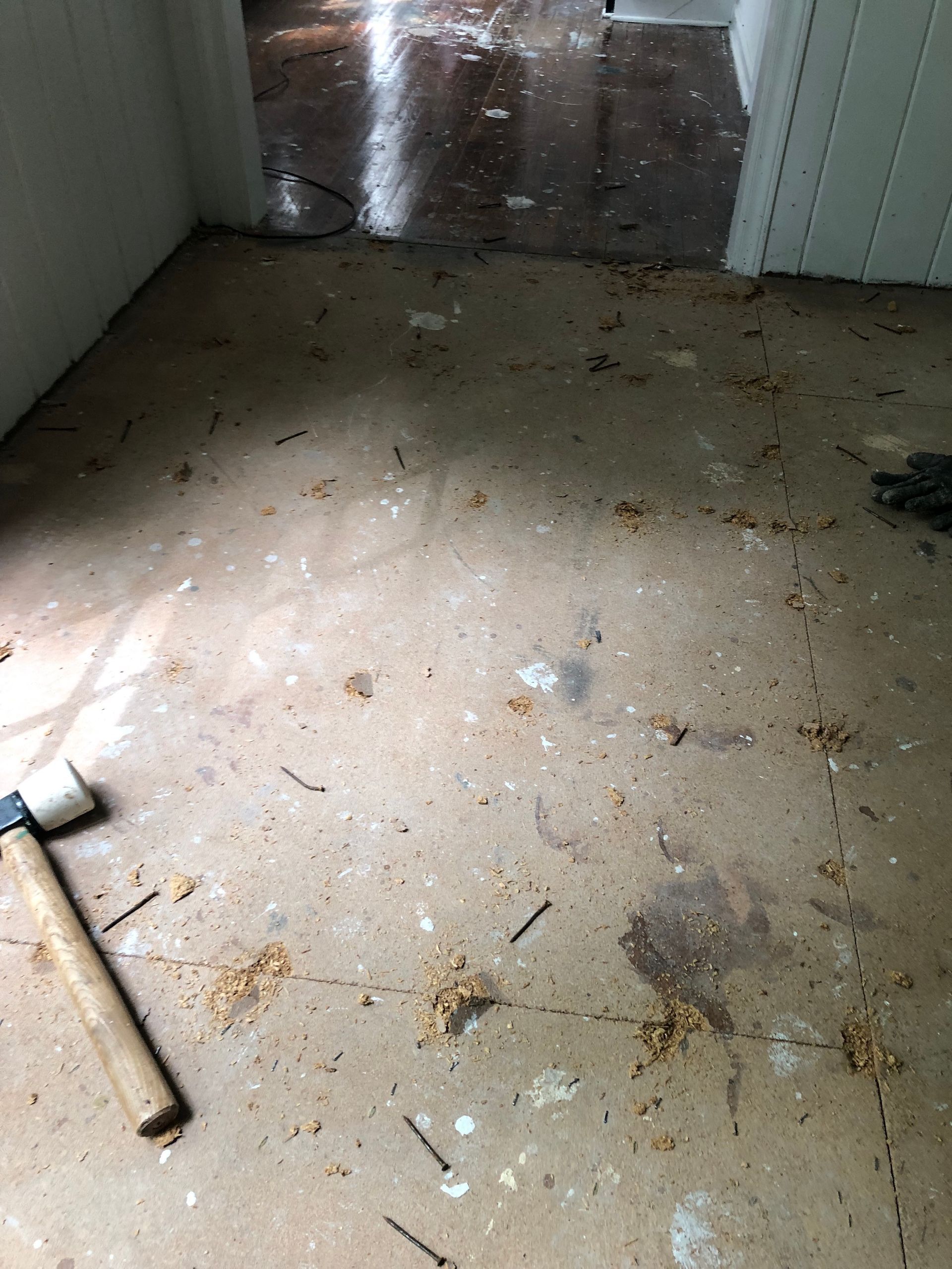 A hammer is sitting on a dirty floor in a room.