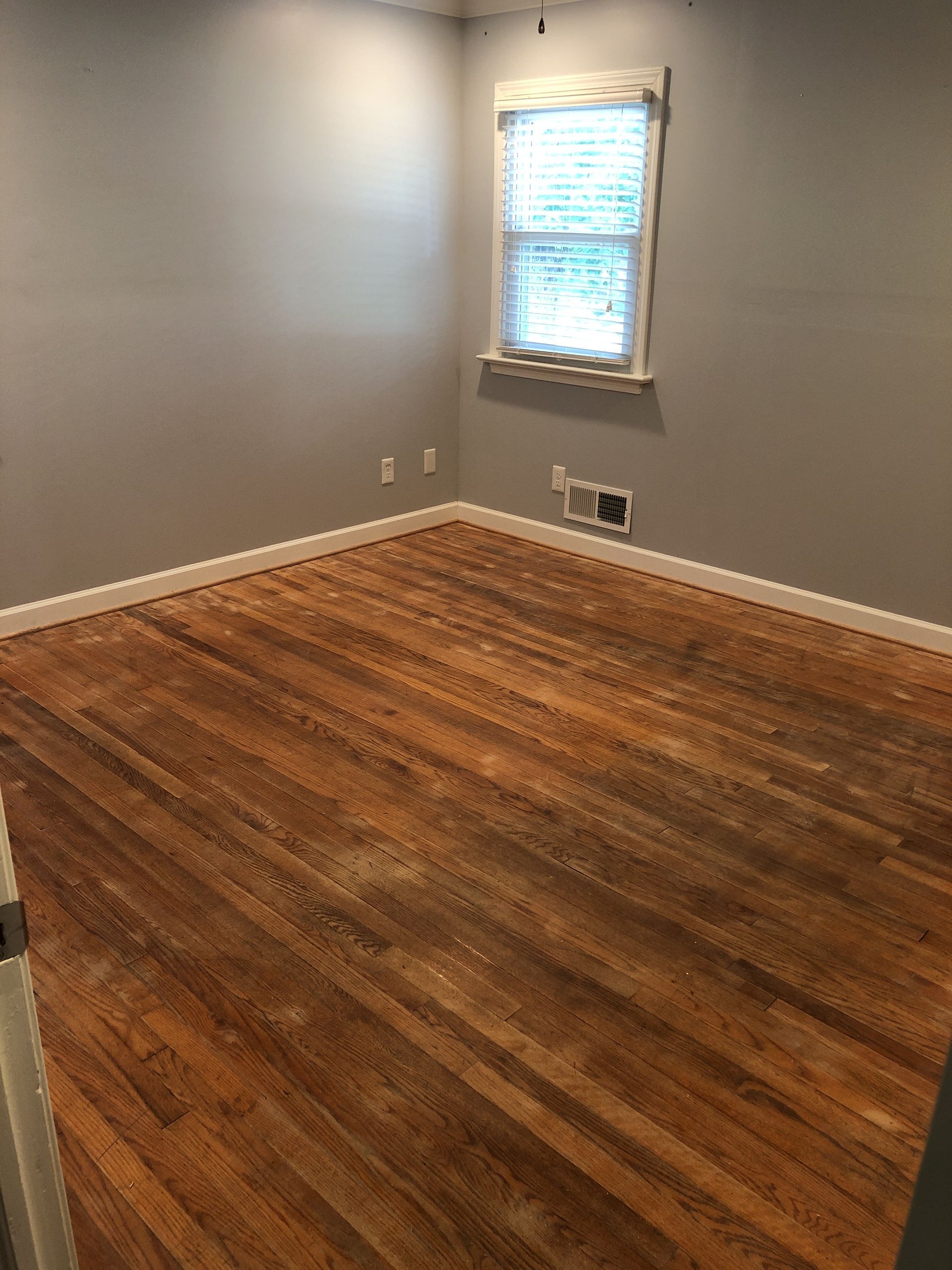 An empty room with hardwood floors and a window.