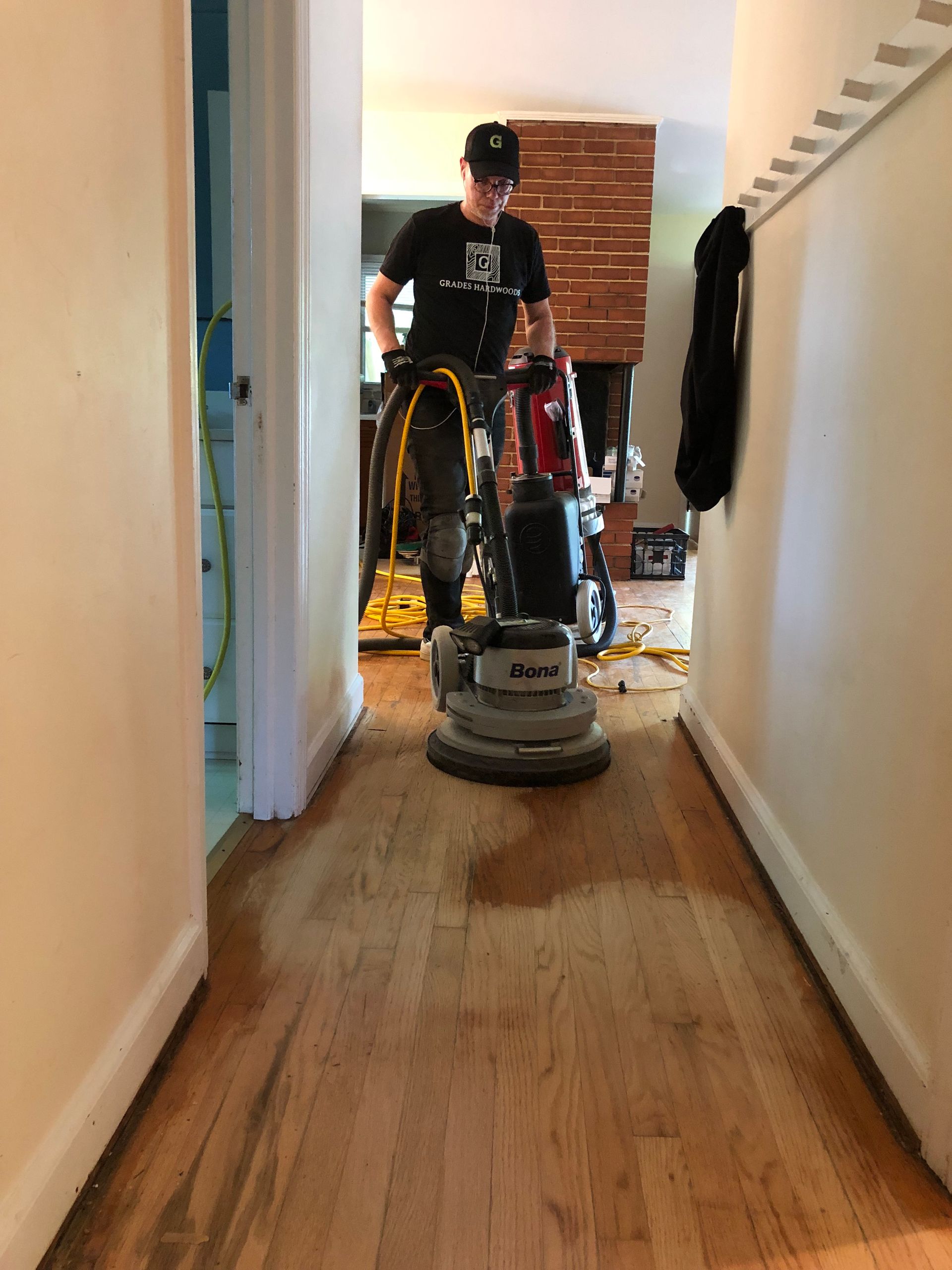 A man is using a floor sanding machine to sand a wooden floor