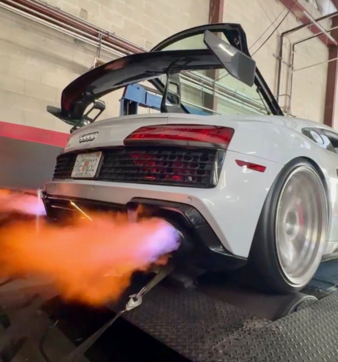 White Audi R8 on a dynamometer, exhaust flames erupting, open gullwing door. | Midnite Tuning