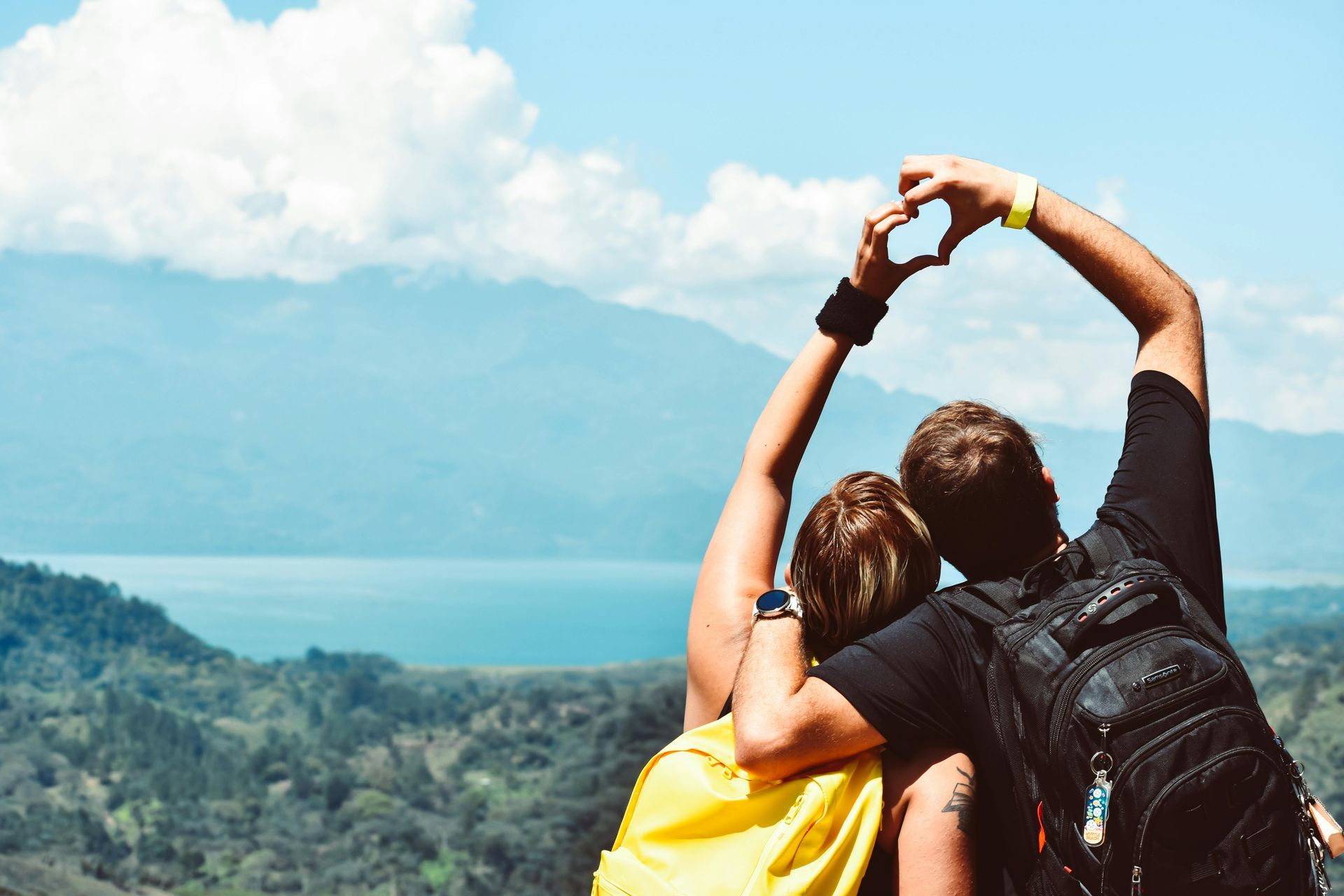 A man and a woman are making a heart shape with their hands.