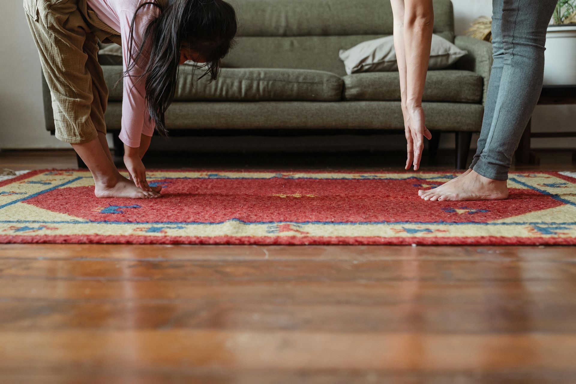 A group of people are doing yoga on a rug in a living room.