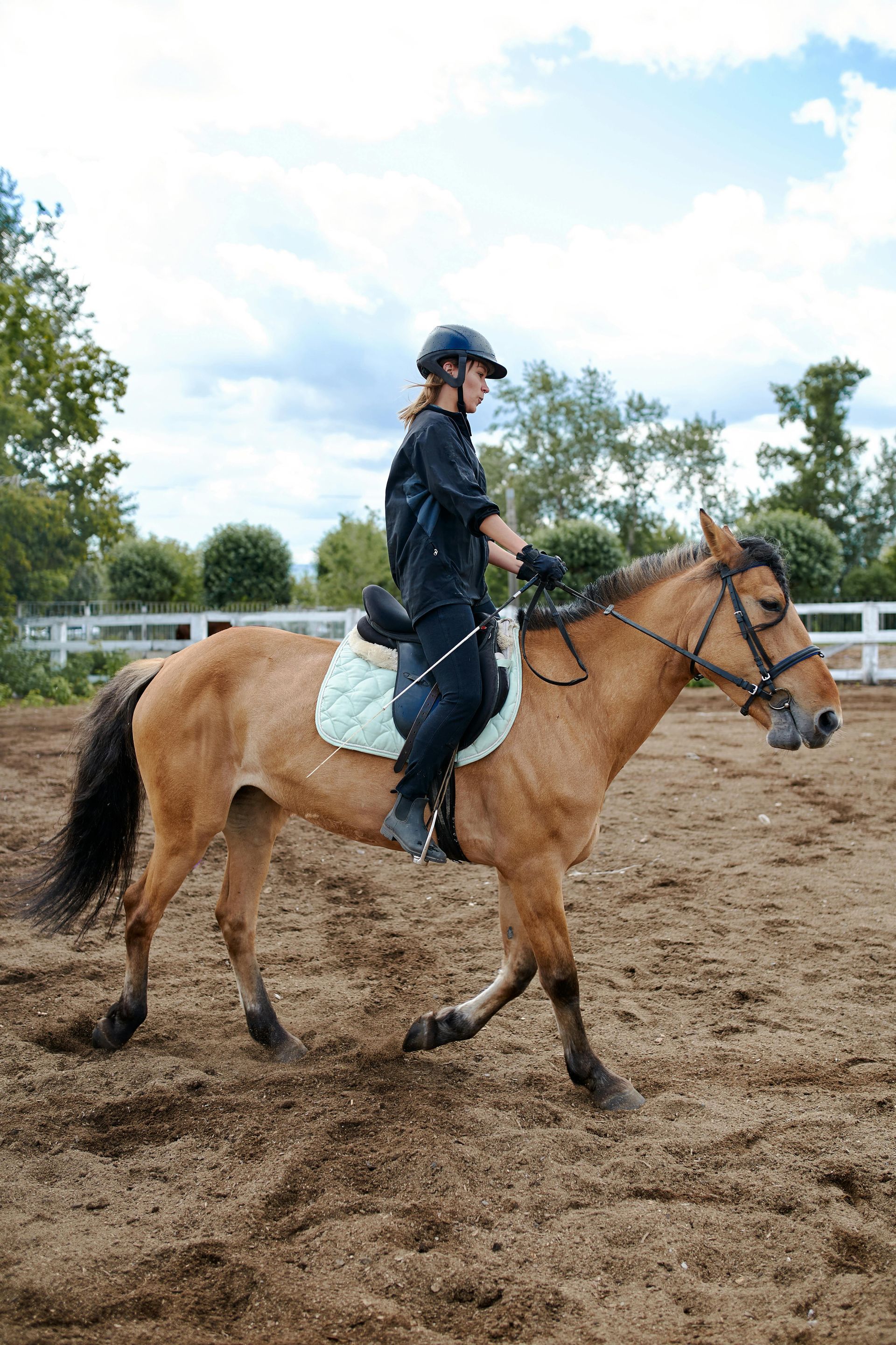 A woman is riding a horse in a dirt field.