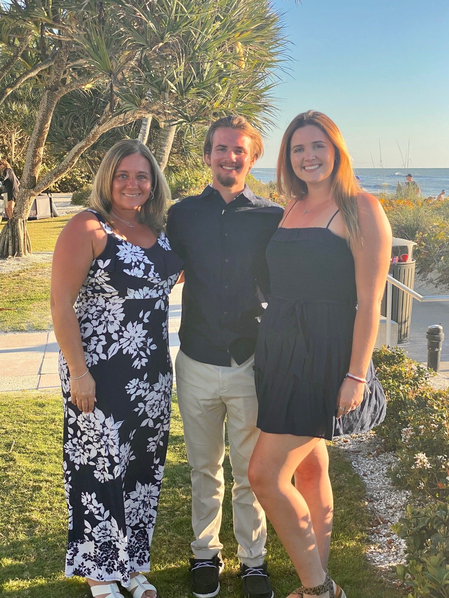 Three people smiling, posed outside.