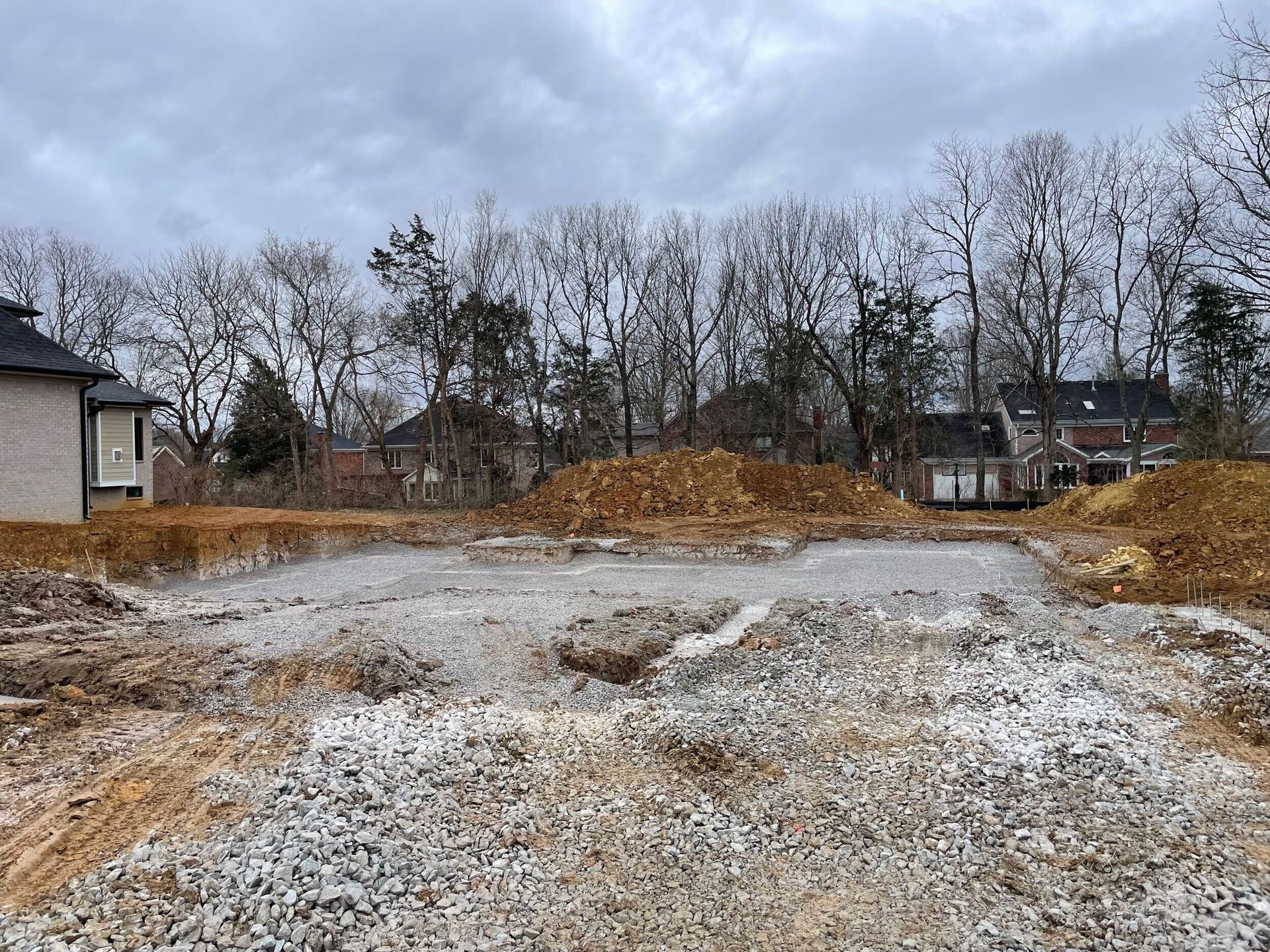 A construction site with a house in the background and trees in the background.