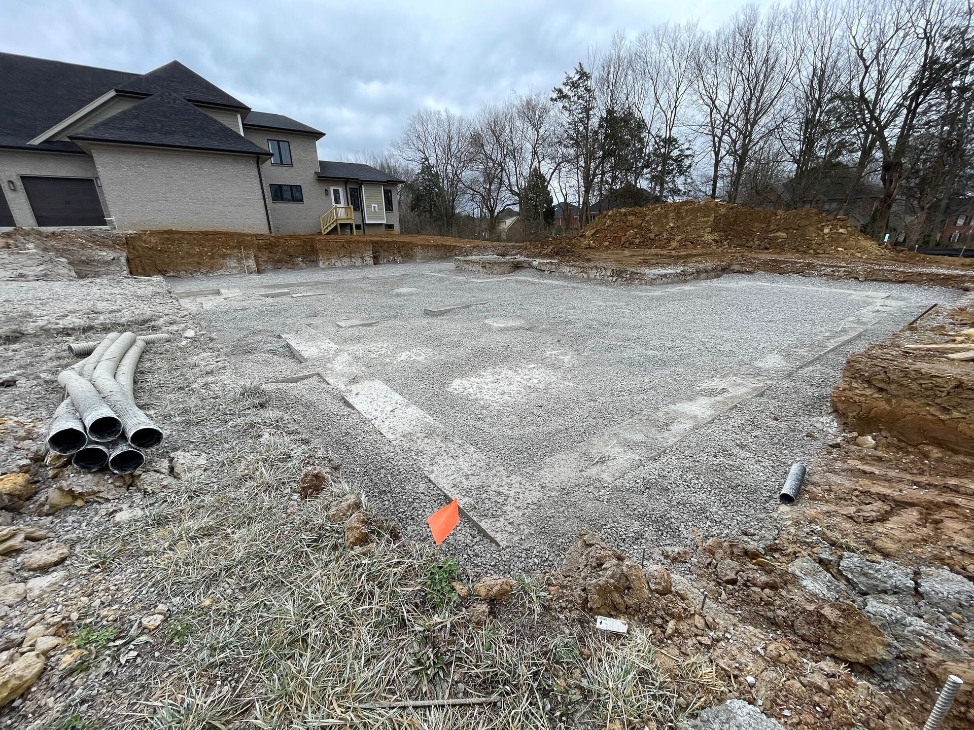 A large house is being built on a gravel lot.