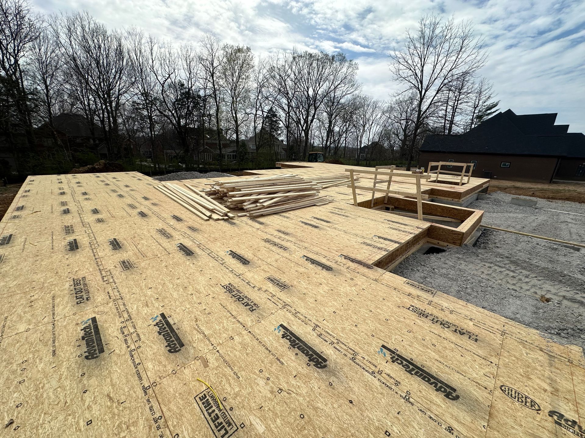 A house is being built on a lot with a lot of wood on the ground.