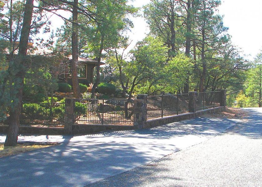 A fence along the side of a road surrounded by trees