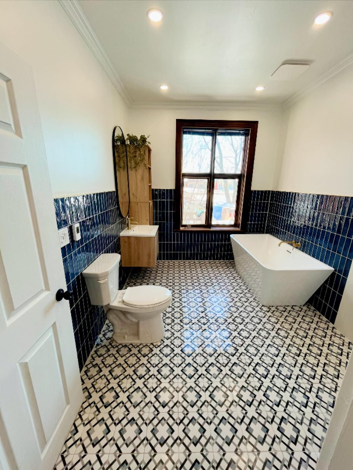 Une salle de bain avec WC, baignoire, lavabo et fenêtre.