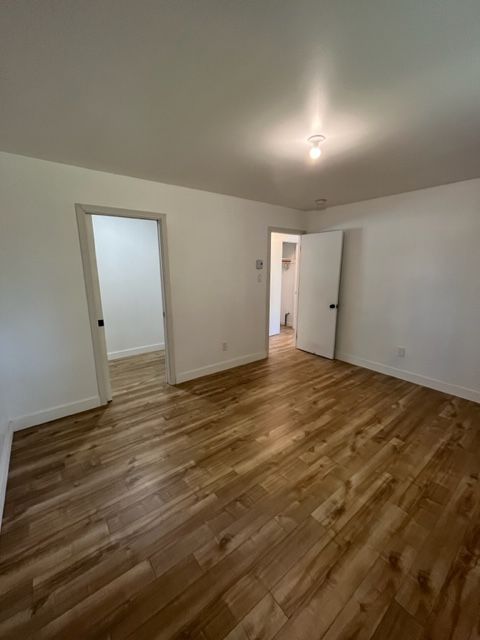 Une pièce vide avec du parquet et des murs blancs.