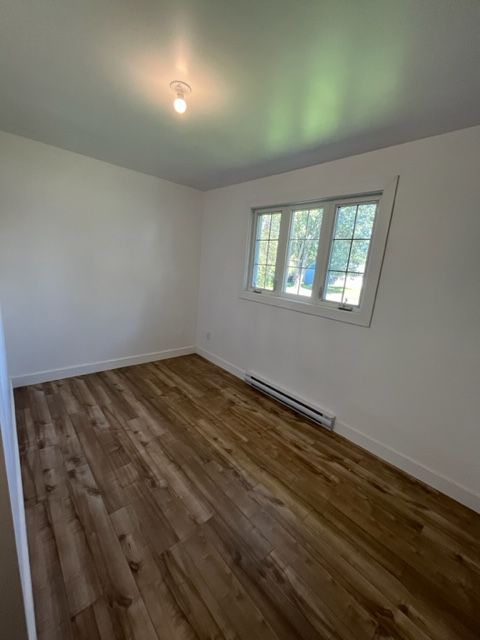 Une pièce vide avec du parquet et des murs blancs.