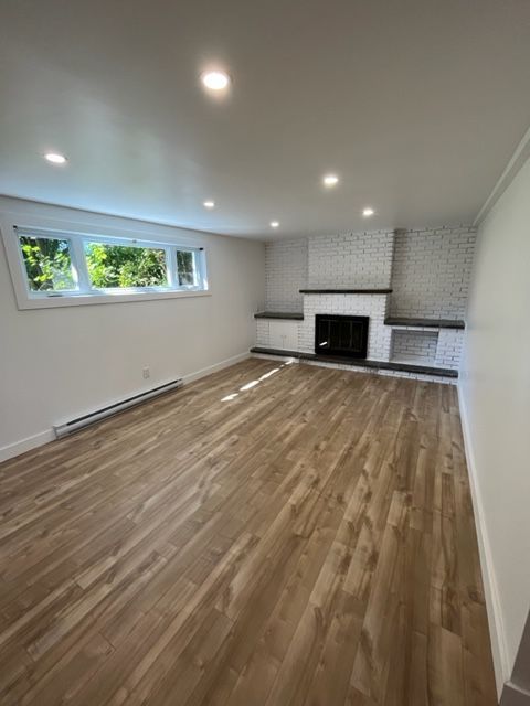 Un salon vide avec du parquet et une cheminée.