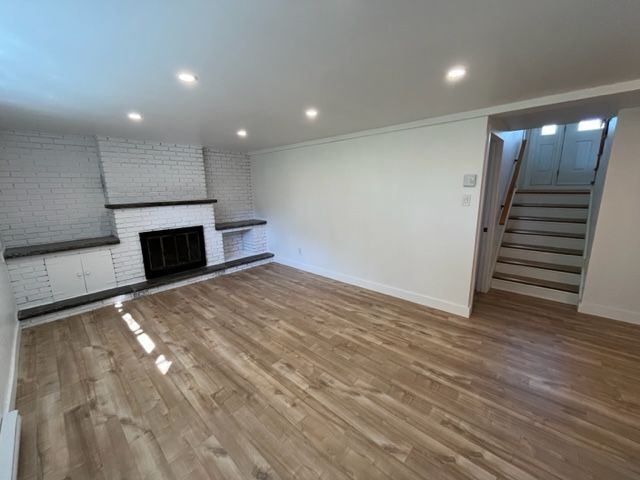 Un salon vide avec une cheminée et des escaliers.