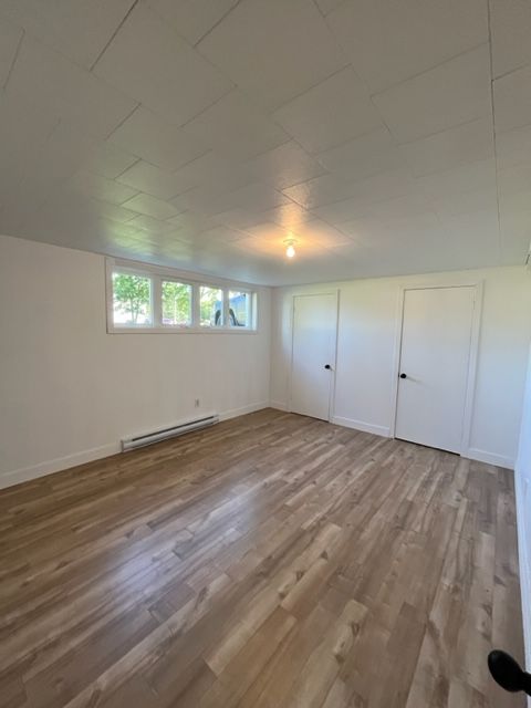 Une grande pièce vide avec du parquet et des murs blancs.