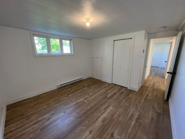 Une pièce vide avec du parquet et des murs blancs.