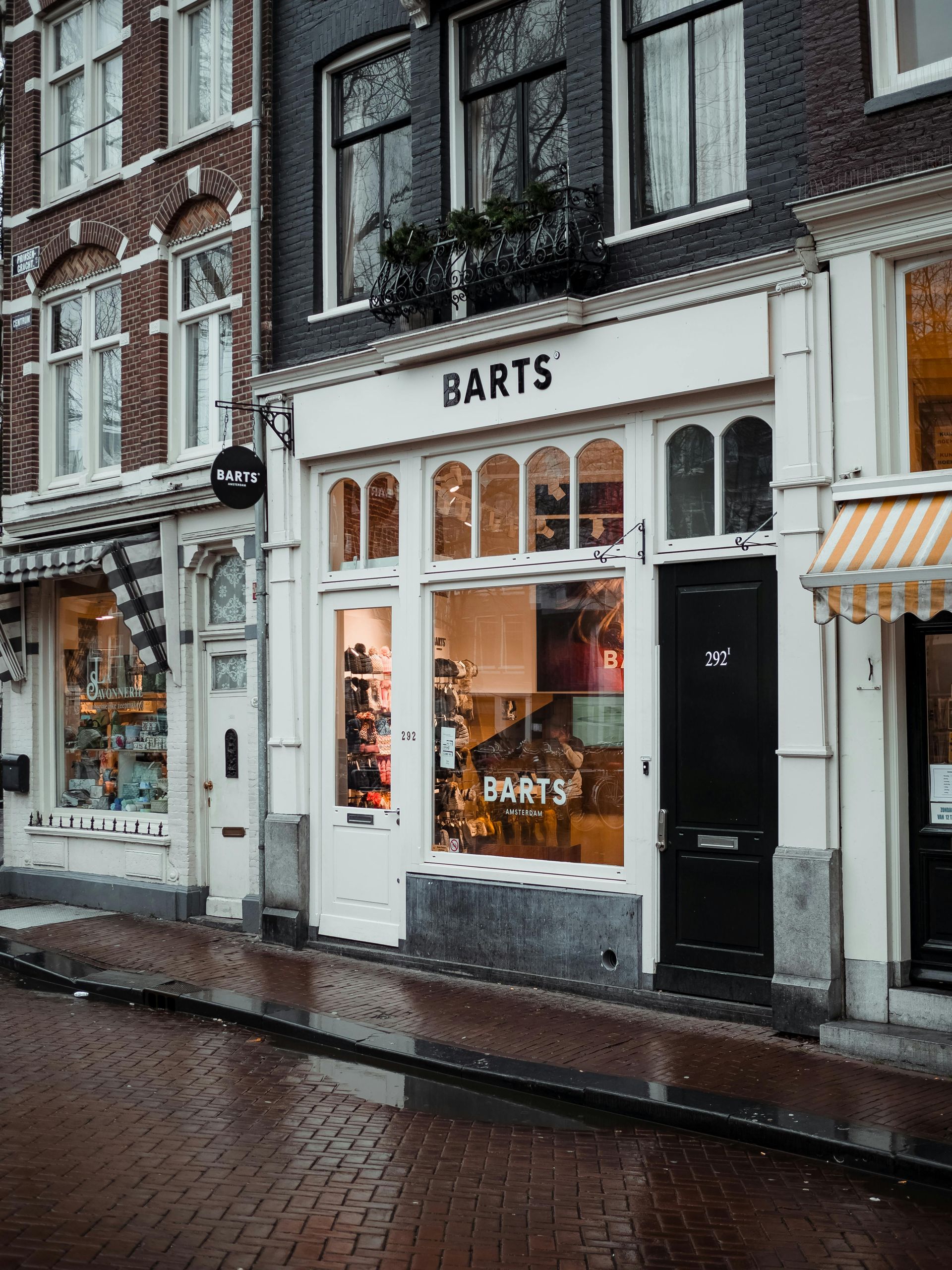 Extérieur du magasin « Barts » à Amsterdam, aux Pays-Bas. Façade blanche avec fenêtres cintrées, porte noire et présentoirs.
