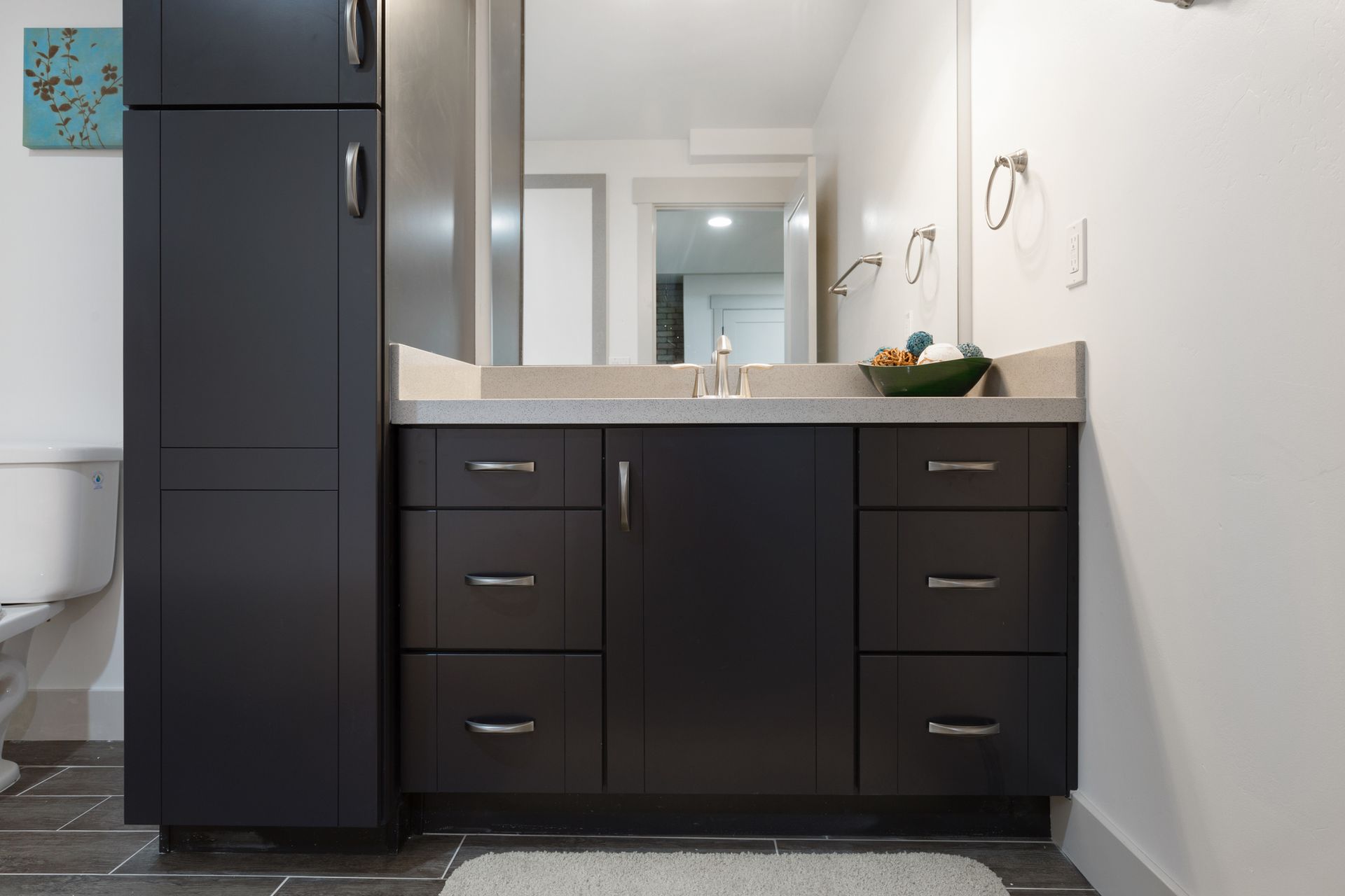 Bathroom with dark cabinets amidst a white setting.