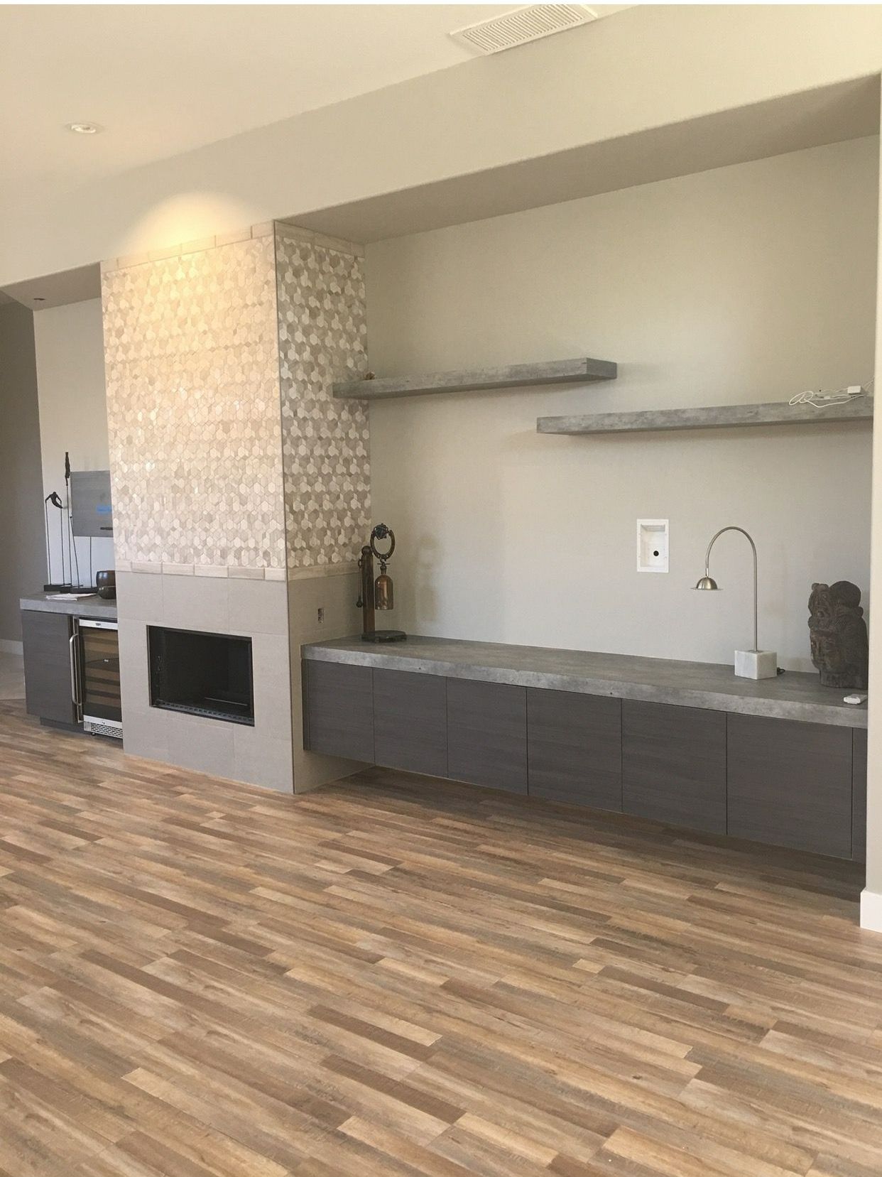 Modern living room with fireplace, built-in shelves, and dark gray cabinets, on wood-look floor.