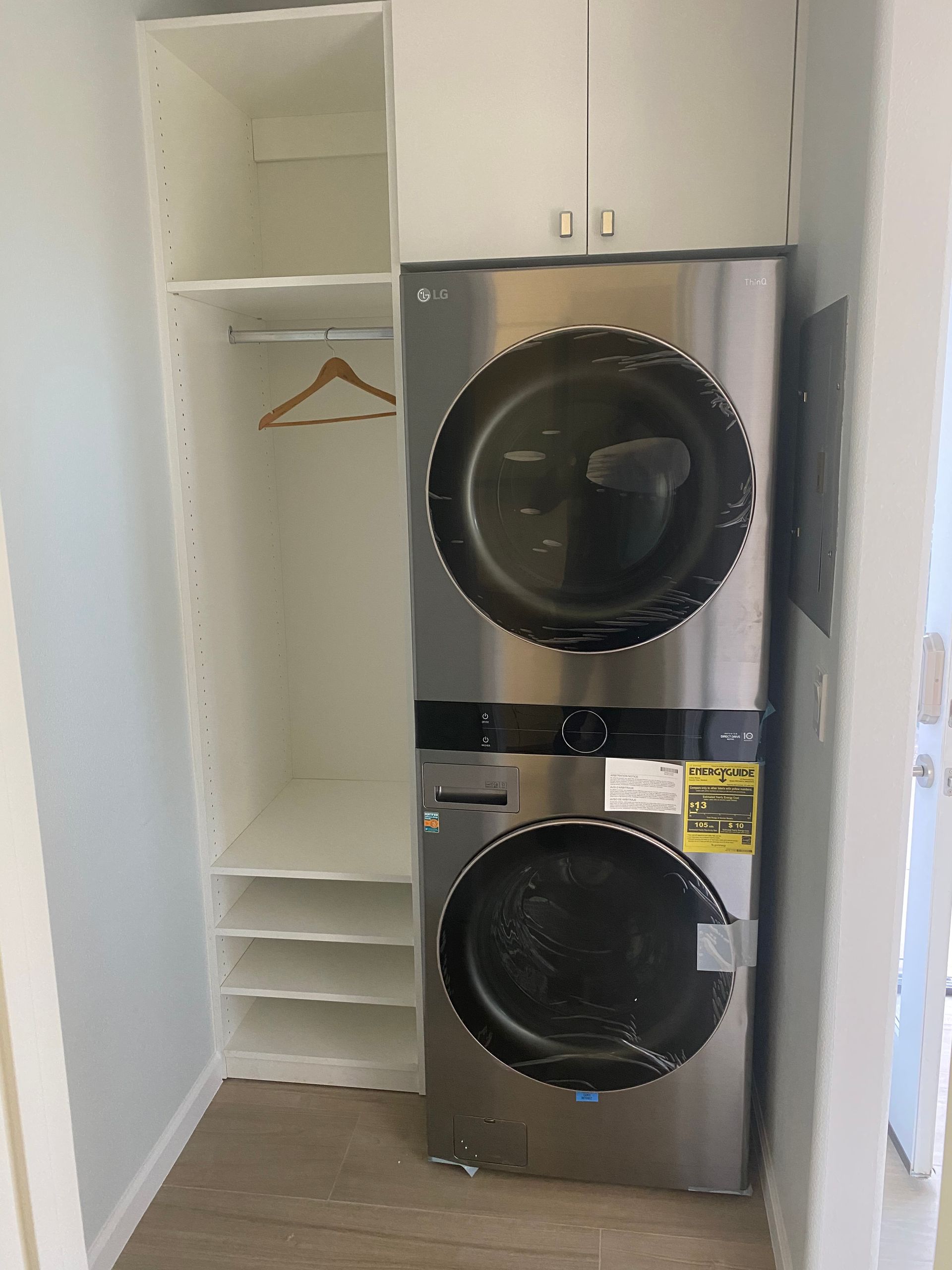 Stackable LG washer and dryer in a small laundry closet with shelves.