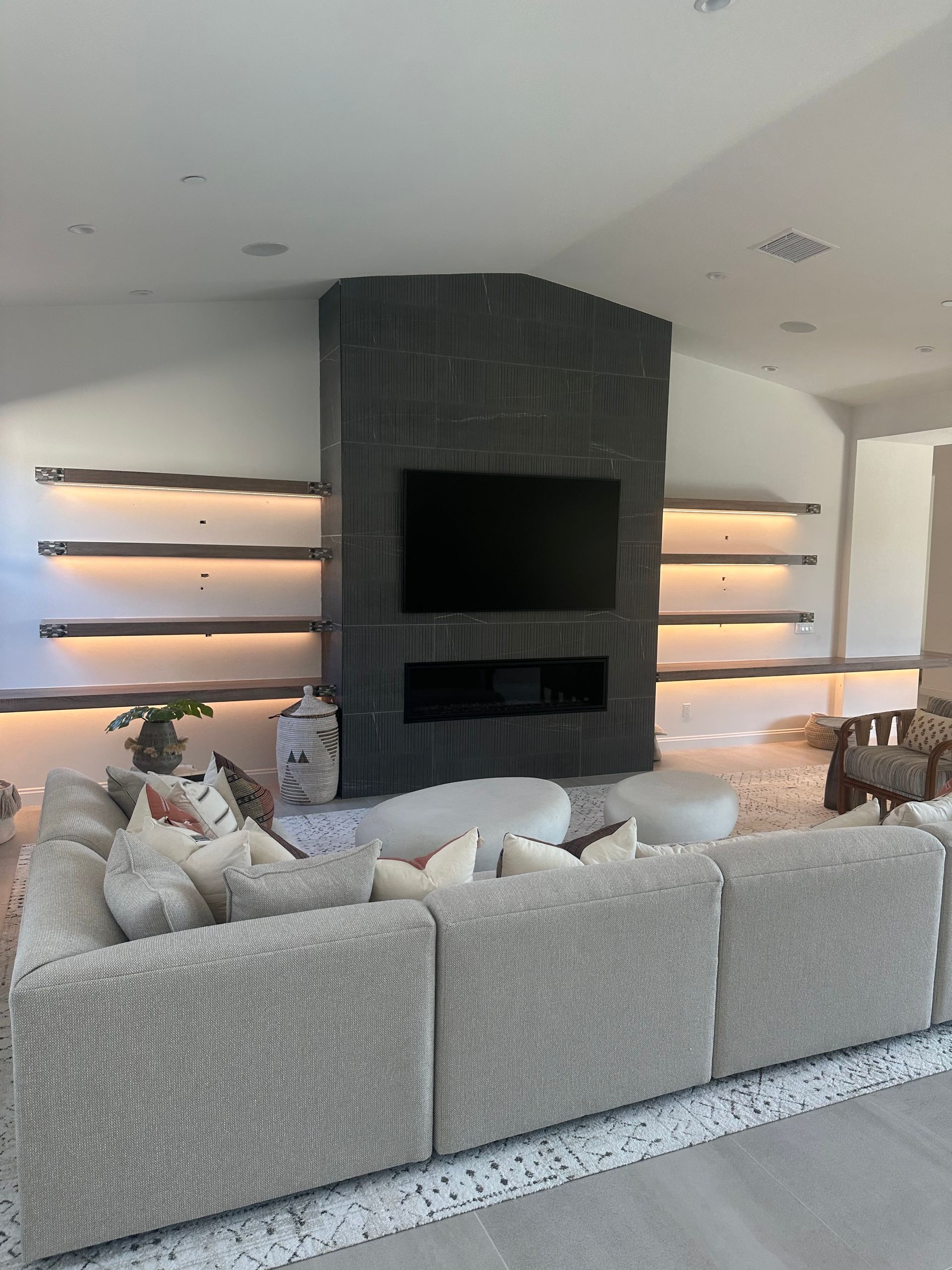 Modern living room with fireplace, built-in shelves, large sectional sofa, neutral tones.