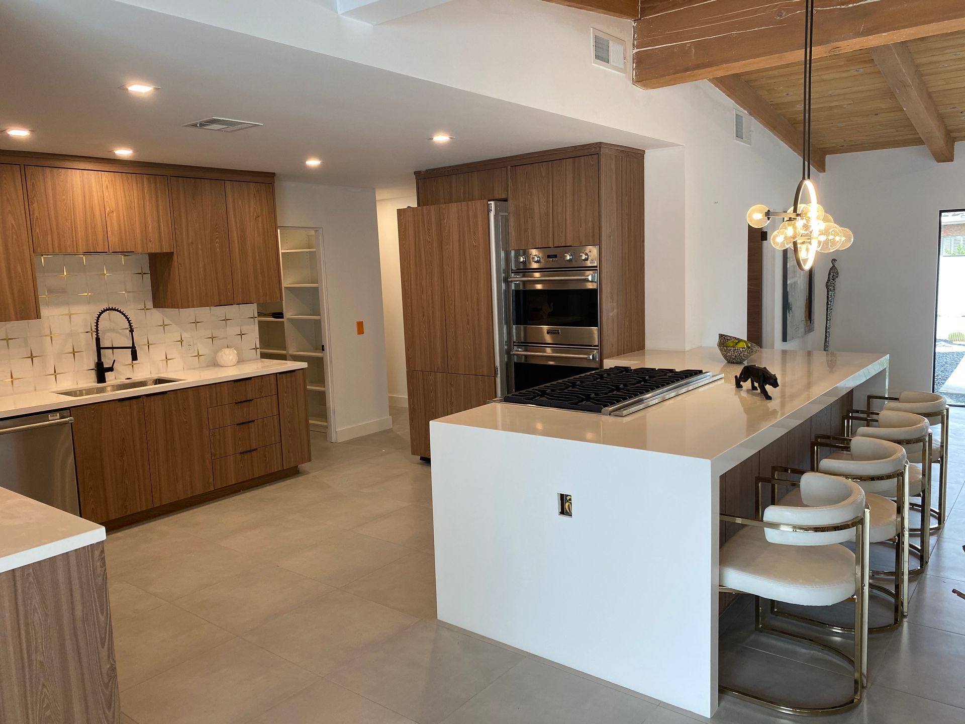 Modern kitchen with light wood cabinets, white countertops, and an island with bar stools.
