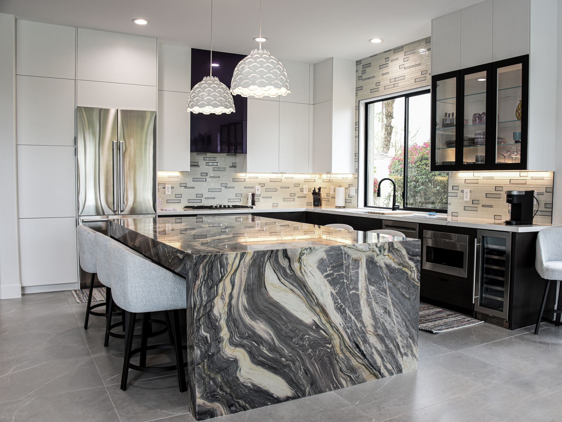 Modern kitchen with a large island, stainless steel appliances, and white cabinetry.
